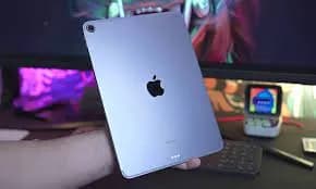 A person holding an ipad in front of a computer